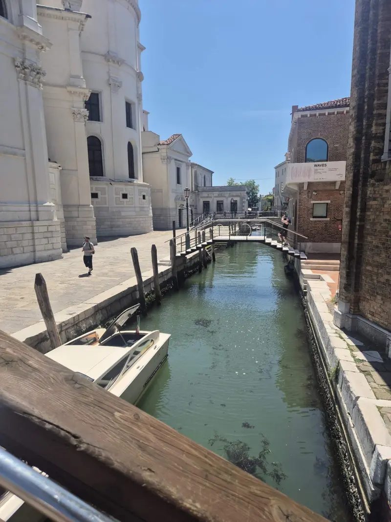 A quiet canal beside Santa Maria della Salute in Dorsoduro, with a moored motorboat and a small footbridge