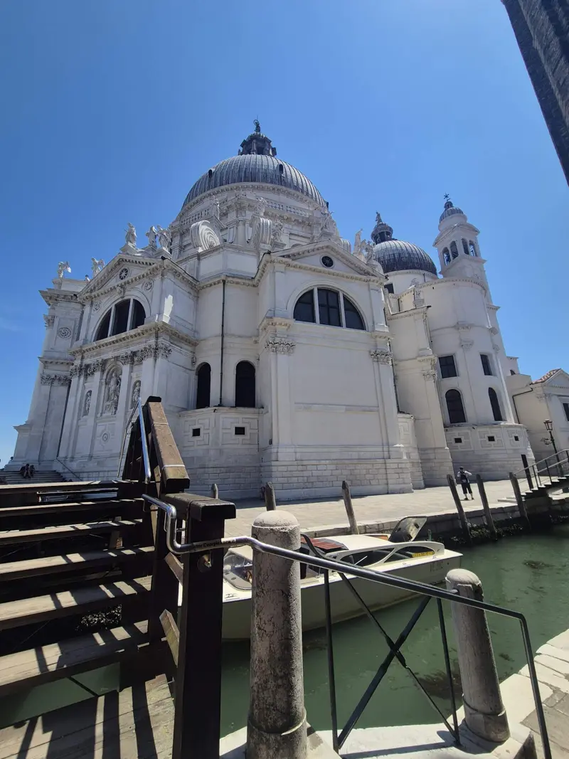 Basilica of Santa Maria della Salute under a blue sky, seen from a side canal